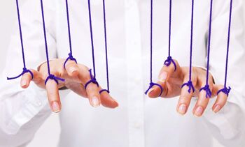 Buste d'une personne avec une chemise blanche. Chaque doigt de ses deux mains en avant plan est retenu par une cordelette suspendue de couleur violette.