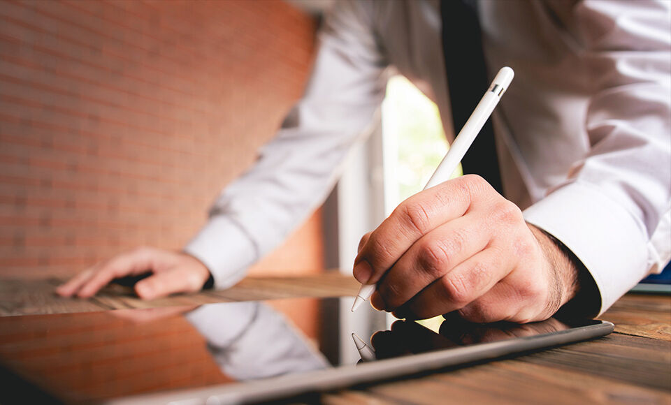 homme &eacute;crivant avec un stylet sur une tablette
