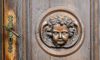 vieille porte en bois avec un visage d'ange sculpté et avec une poignée dorée