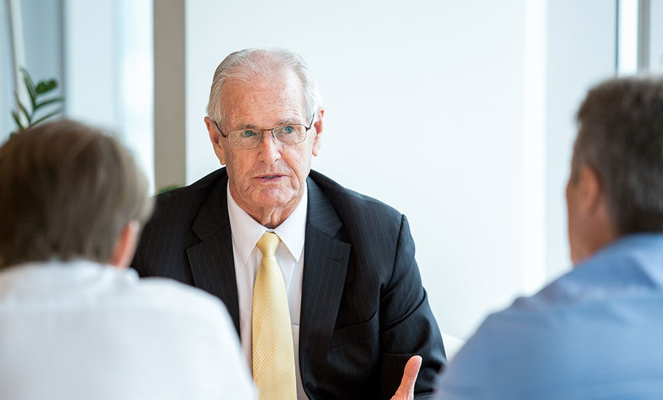 un homme face à deux autres hommes assis dans une salle de réunion