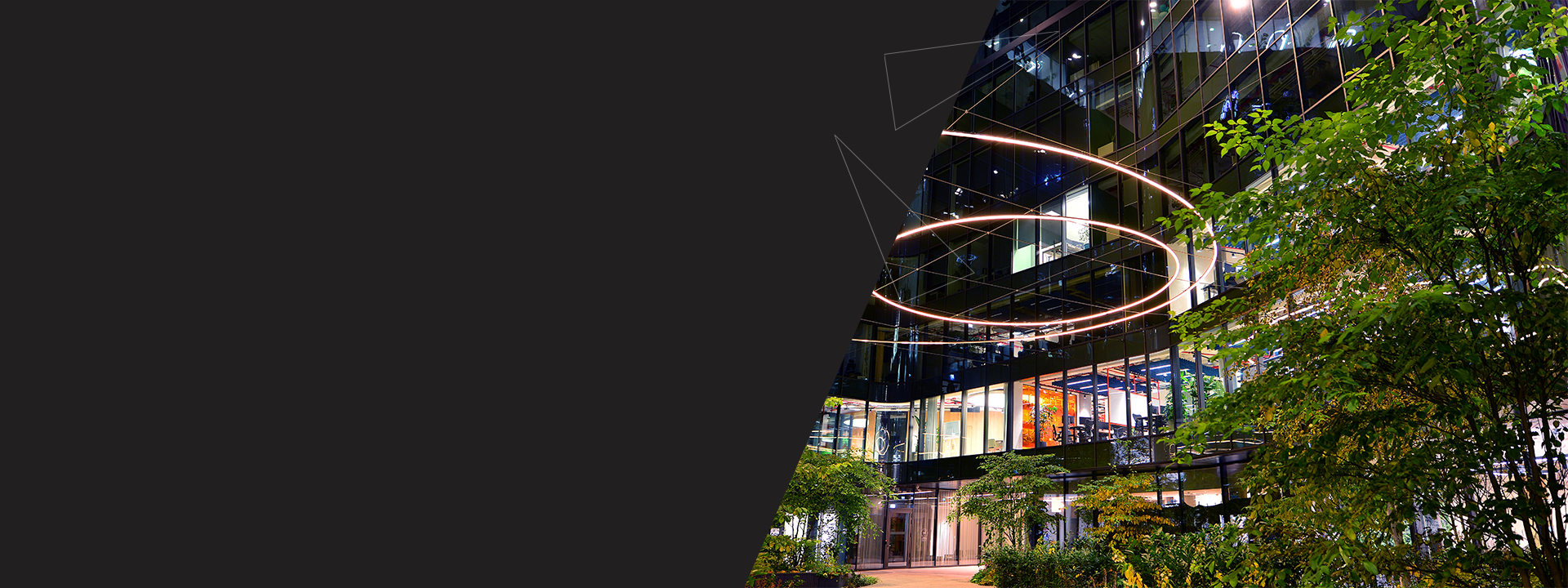 immeuble illumin&eacute; avec des arbres - Accompagner la transition environnementale de votre entreprise