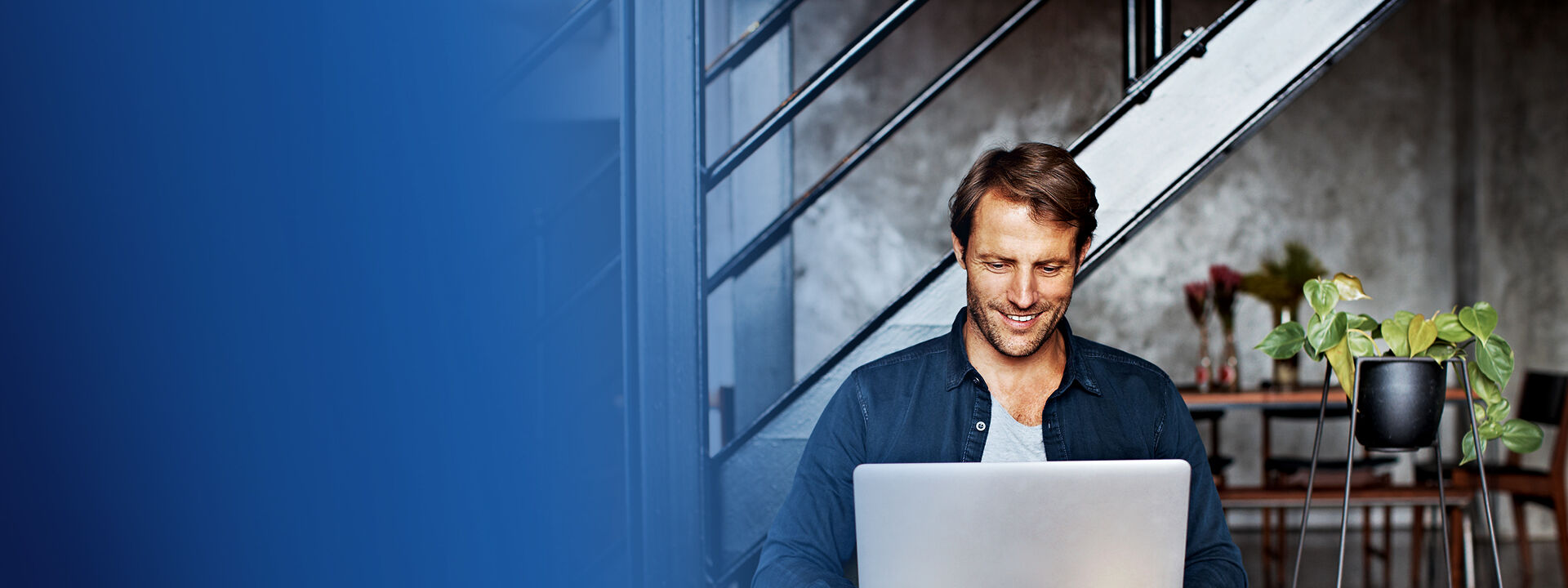 Homme qui sourit et qui est devant son ordinateur