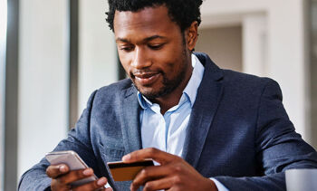 Homme en costar qui tient une carte bancaire et un téléphone dans les mains