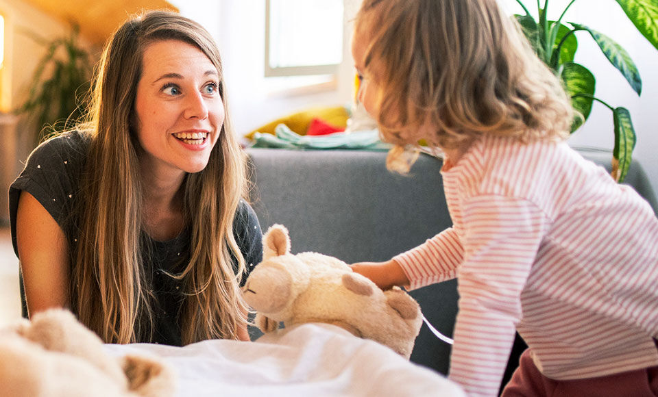 jeune femme jouant avec sa fille et sa peluche