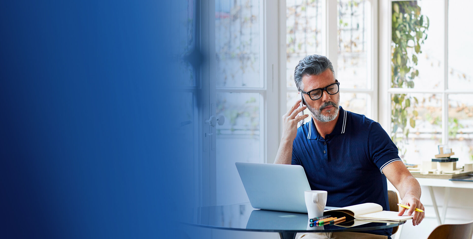 banniere homme active &agrave; lunette tenant un smartphone et travaillant devant un laptop