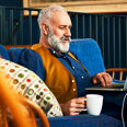 Homme d'age mur barbu travaillant sur son ordinateur avec un cafe
