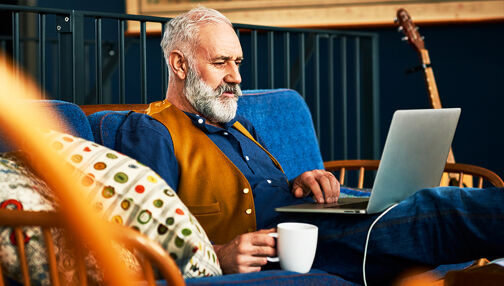 Homme d'age mur barbu travaillant sur son ordinateur avec un cafe