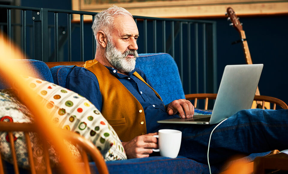 Homme d'age mur barbu travaillant sur son ordinateur avec un cafe