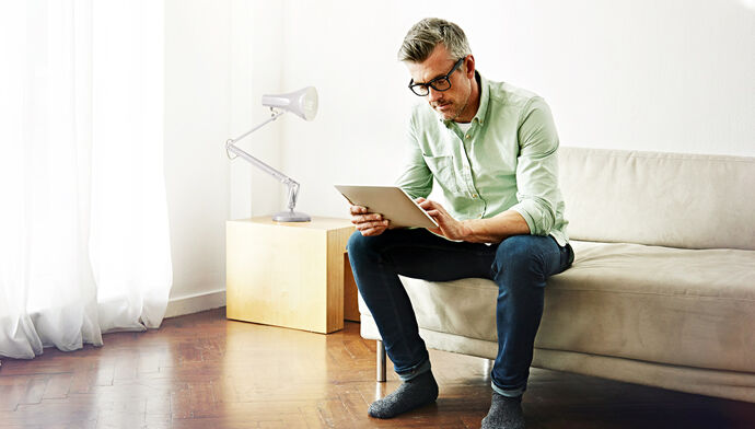 jeune homme souriant concentré tablette