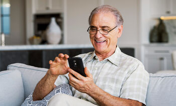 Homme agé souriant regardant son smartphone
