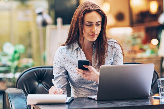 jeune femme active travaillant sur un ordinateur et son telephone