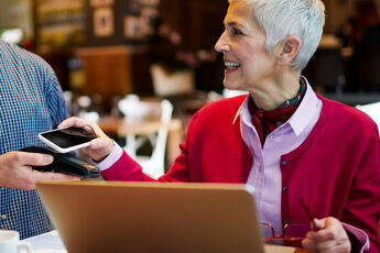 Femme mure souriante Paie par carte avec mon mobile