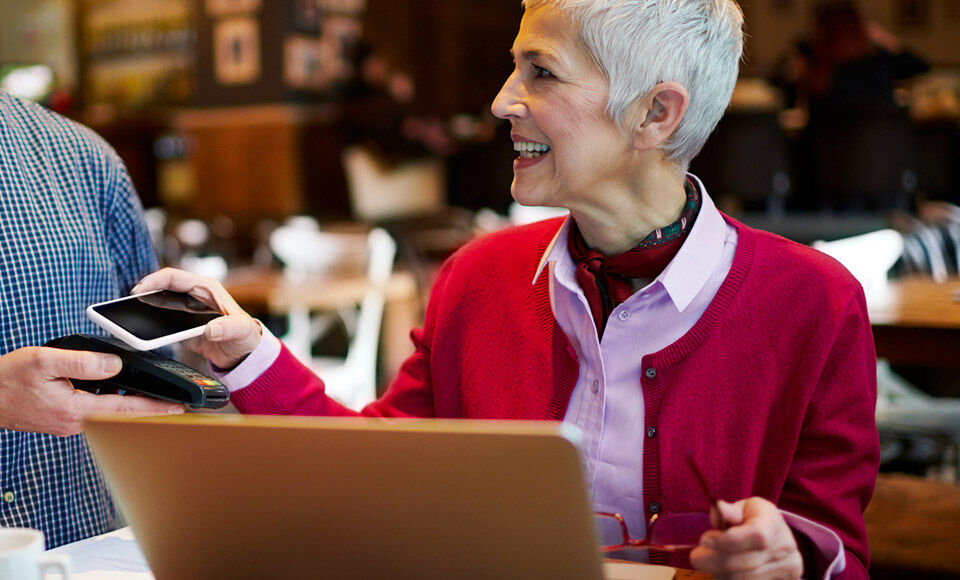 Femme mure souriante Paie par carte avec mon mobile