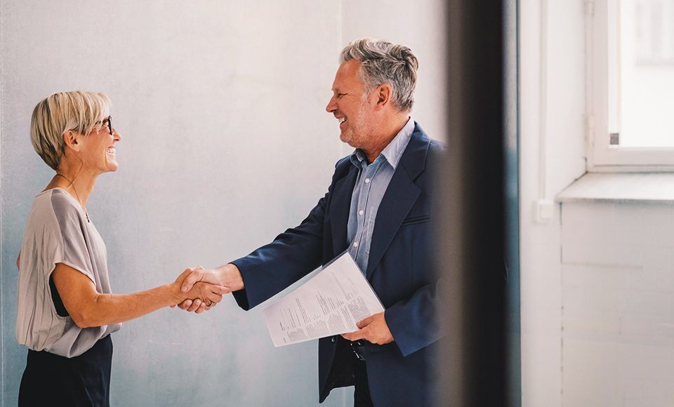 Femme mure serrant la main d'un homme mure apres signature de contrat