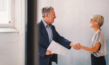 Femme mure serrant la main d'un homme mure apres signature de contrat