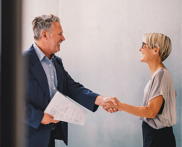 Femme mure serrant la main d'un homme mure apres signature de contrat