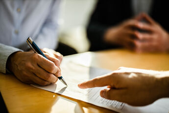 Gros plan sur une personne méconnaissable signant un contrat.