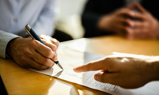 Gros plan sur une personne méconnaissable signant un contrat.