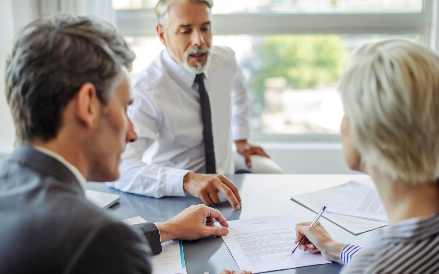 Femme signant un document lors d'une réunion avec des professionnels