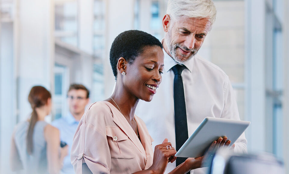 Homme mur discutant avec femme souriante tenant une tablette