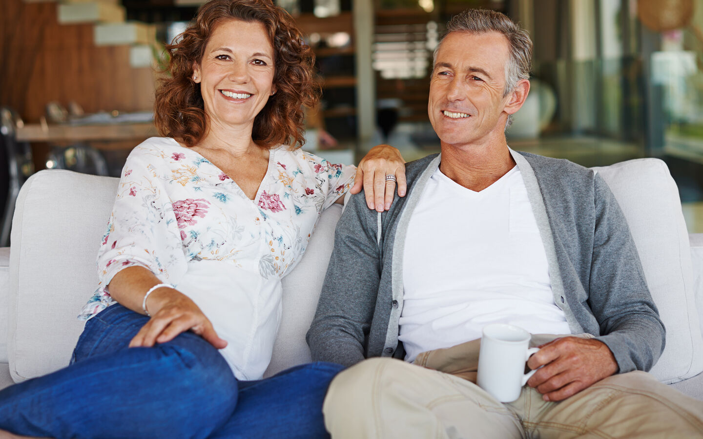 homme et femme mures souriant assis canapé