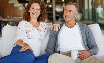 homme et femme mures souriant assis canapé