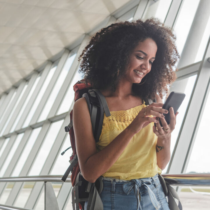Jeune femme avec sac à dos vérifiant son horaire d'embarquement à l'aéroport