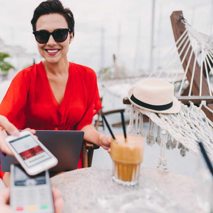 Femme au café de la plage payant sans contact avec smartphone