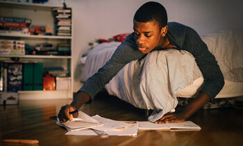 jeune étudiant sur le lit en travaillant