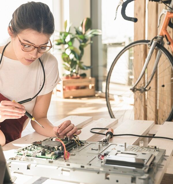 Jeune femme travaillant sur du matériel informatique à la maison à côté d'une tablette