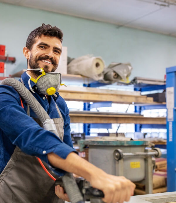 Menuisier souriant à l'aide d'un broyeur en atelier