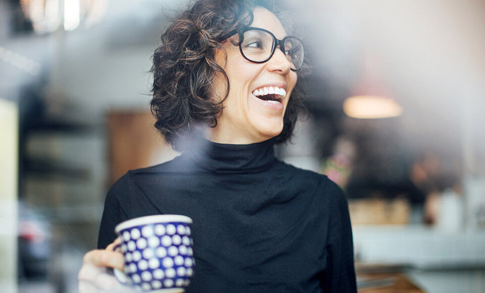Femme a lunette souriante en train de boire du caf&eacute;