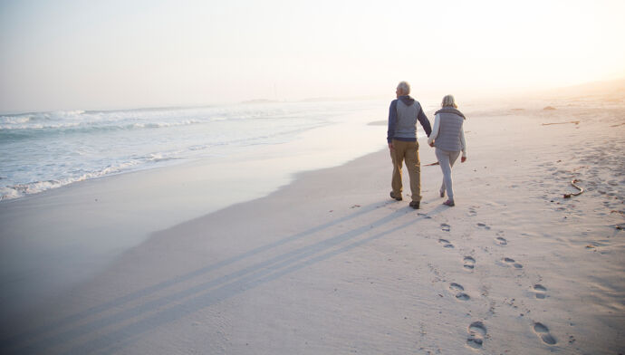 couple se donnant la main marchant vers la mer